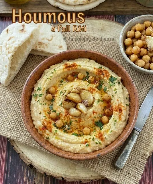 Texture lisse du houmous à l'ail rôti avec filet d'huile d'olive